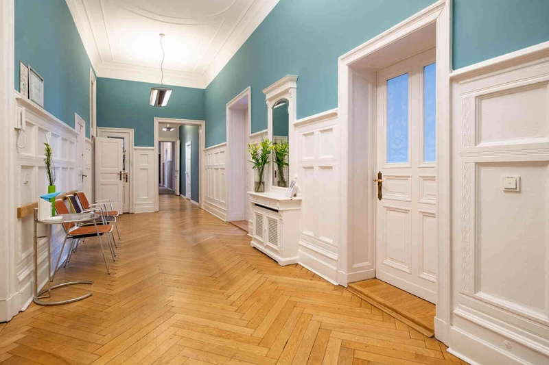 Eingangsbereich der Oberberg Tagesklinik Berlin mit roten Sitzb&auml;nken, Glasfronten und Pflanzen, Blick von au&szlig;en auf die T&uuml;r und Fassade.